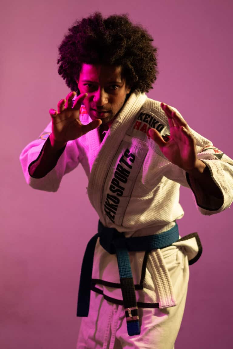 Imagem de uma mulher praticando Jiu-Jitsu com kimono branco e faixa azul, focada e pronta para a lut.