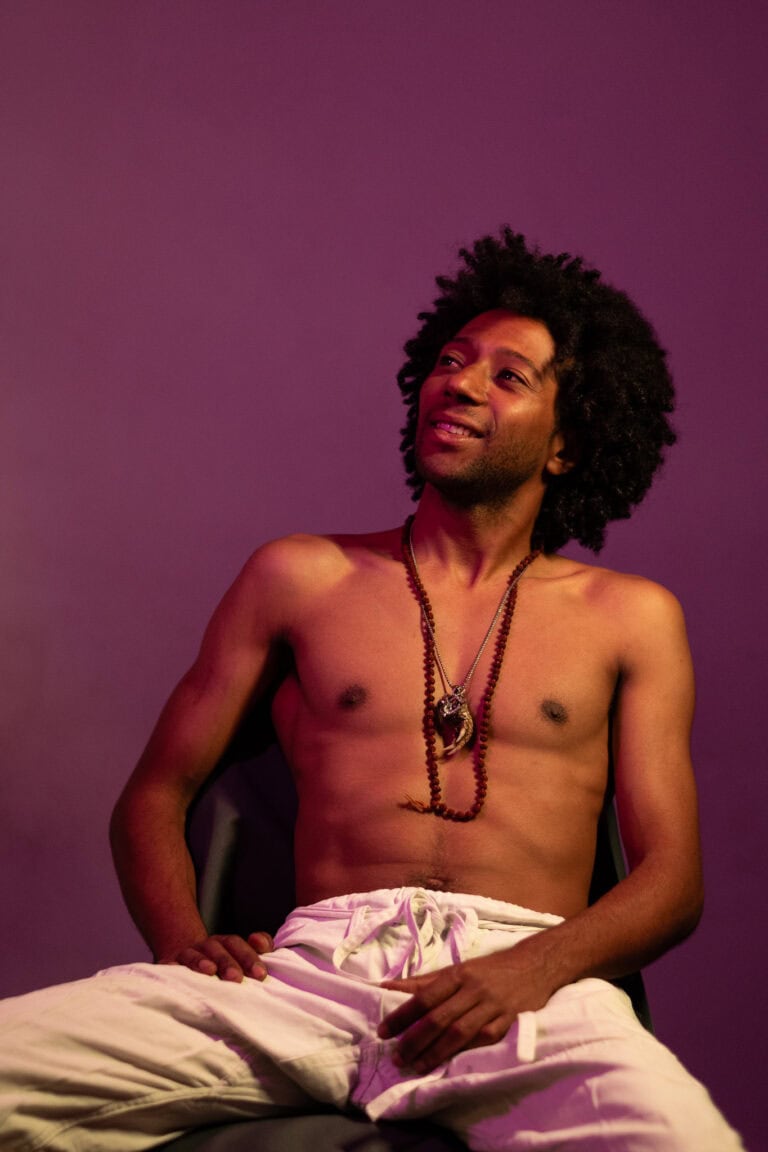 Fotógrafo Guilherme Marques captura retrato artístico de homem com cabelo afro e expressão feliz.