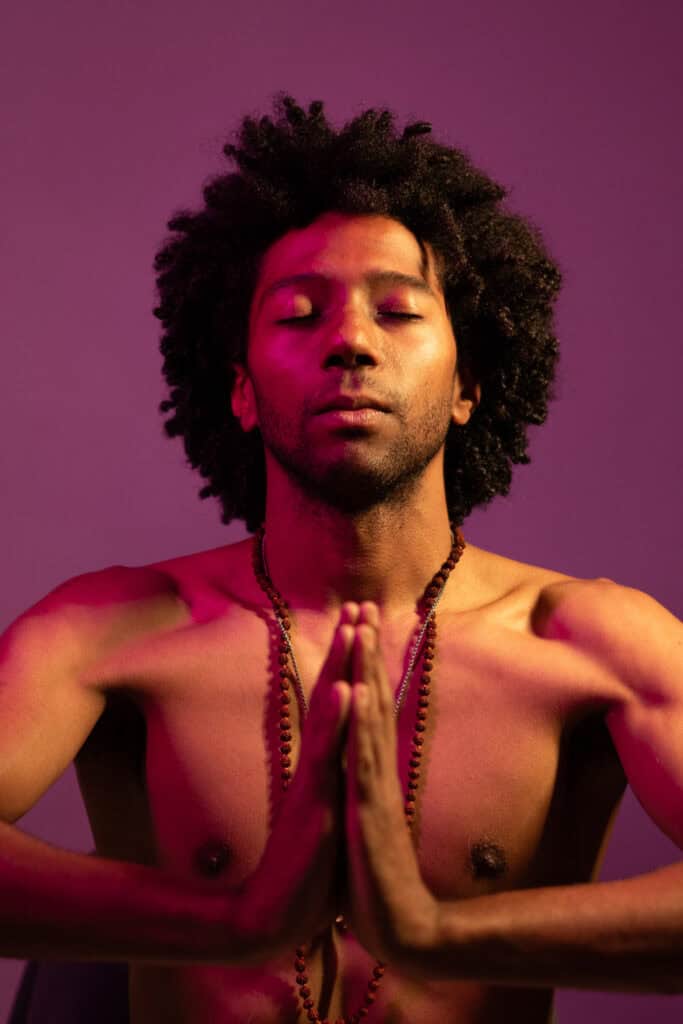 Fotógrafo Guilherme Marques captura um homem em postura de meditação com fundo roxo.