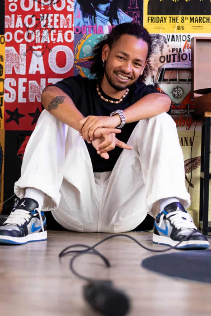 Guilherme Marques, fotógrafo profissional, sorrindo em estúdio com fundo artístico vibrante.