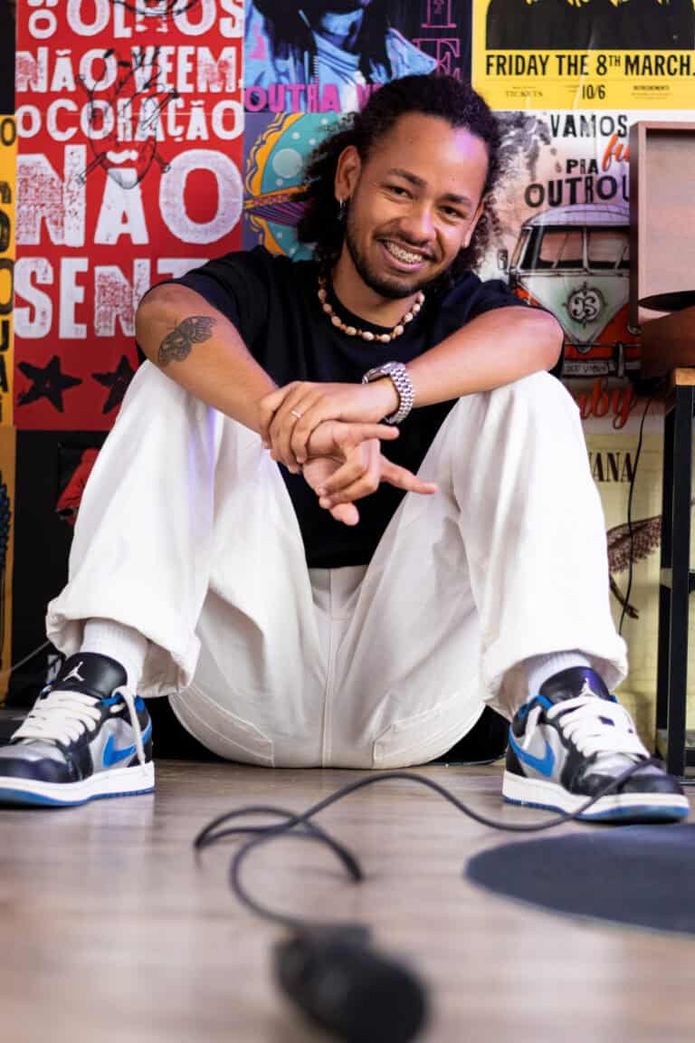Guilherme Marques, fotógrafo profissional, sorrindo em estúdio com fundo artístico vibrante.