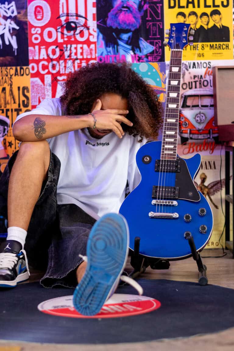 Guitarrista com cabelo afro e guitarra azul em estúdio criativo.