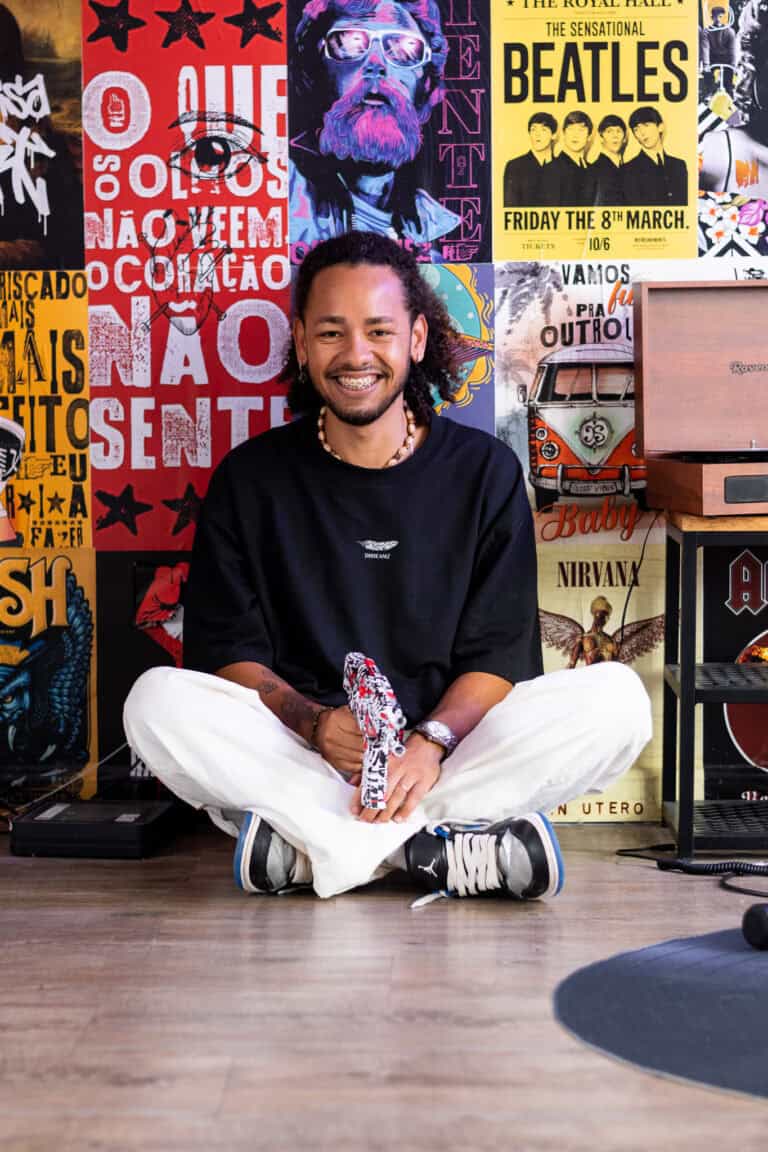 Fotógrafo Guilherme Marques em estúdio com fundo de pôsteres musicais.