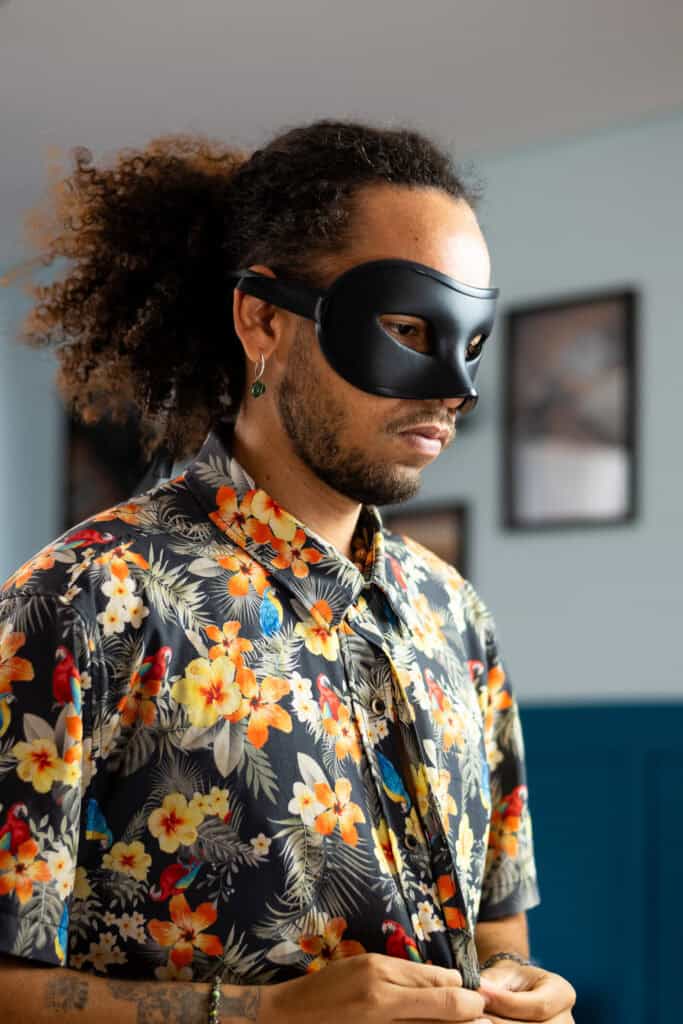 Máscara artística para ensaio fotográfico, retratando um homem com camisa floral e cabelo cacheado,.