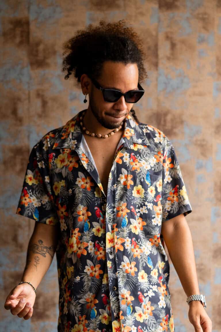 Retrato de homem com estilo casual usando camisa floral e óculos escuros.