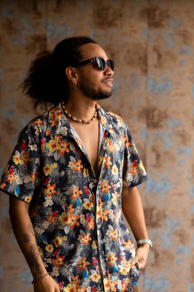 Fotógrafo Guilherme Marques com estilo tropical e casual, usando óculos escuros e camisa floral.