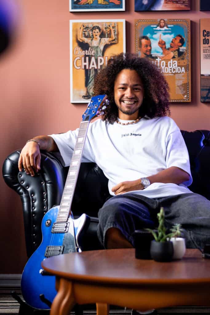 Imagem de Guilherme Marques com violão azul em ambiente de estúdio.
