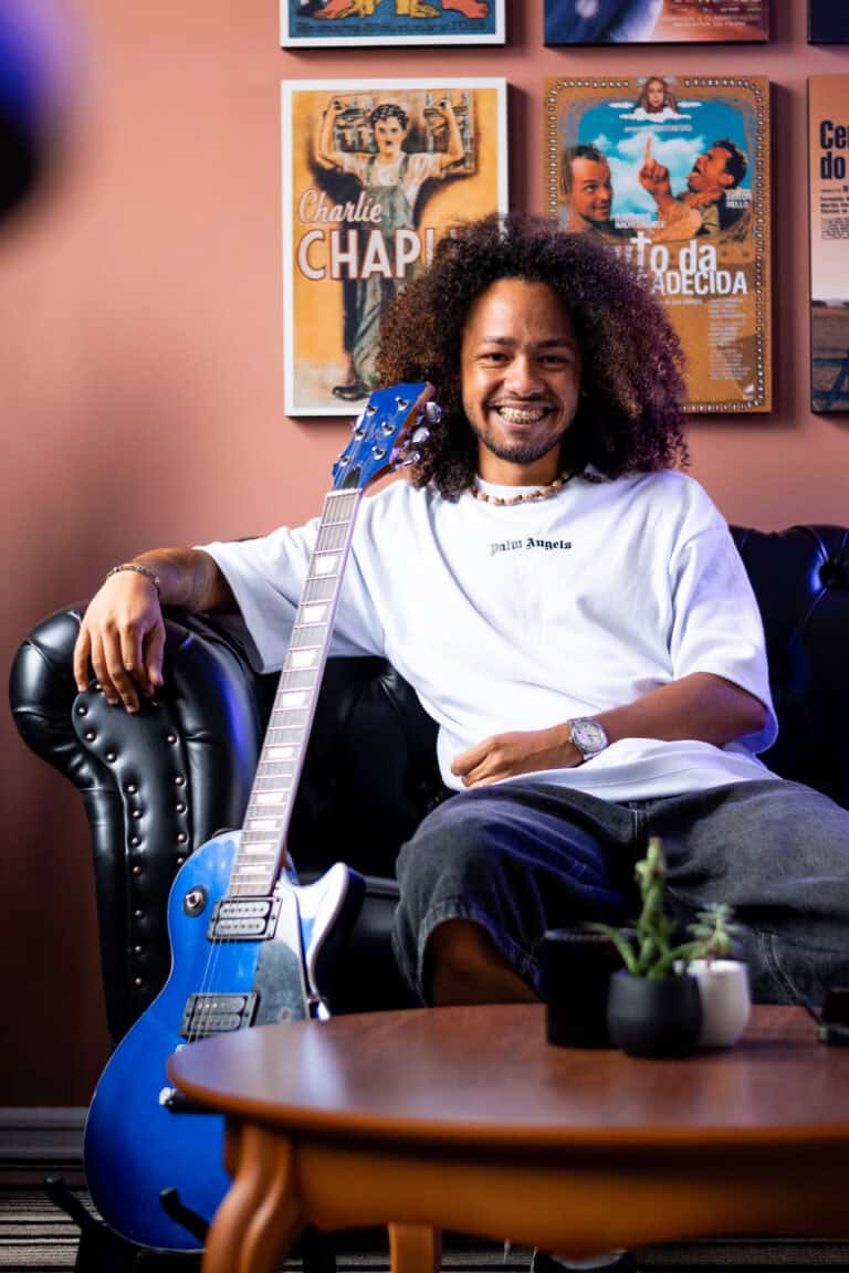 Imagem de Guilherme Marques com violão azul em ambiente de estúdio.
