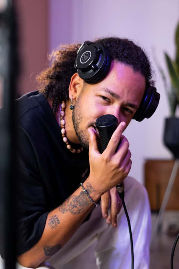 Guilherme Marques com fones de ouvido e microfone em estúdio de fotografia.