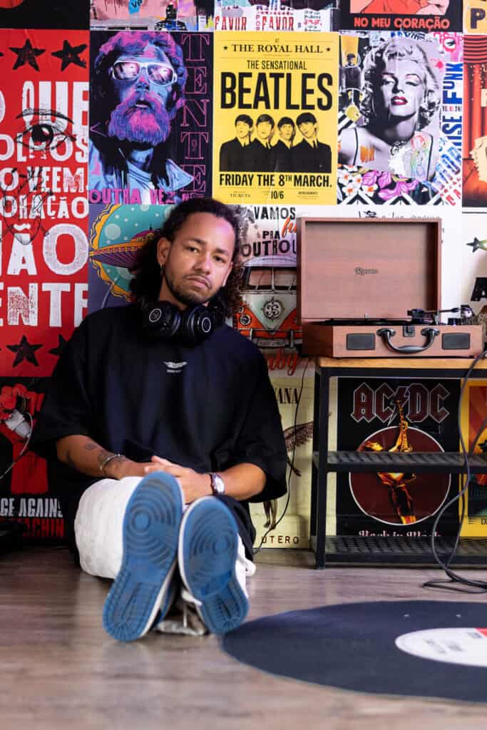 Fotógrafo Guilherme Marques em estúdio com fundo de posters musicais.