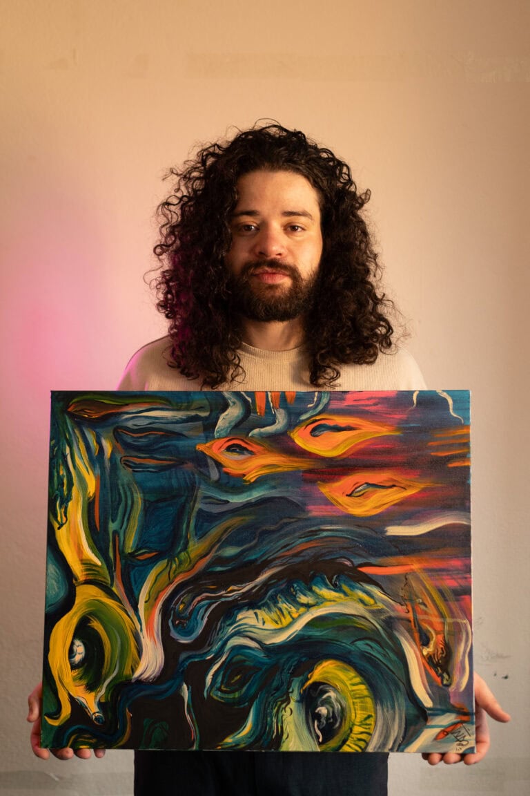 Fotógrafo Guilherme Marques segurando pintura artística.
