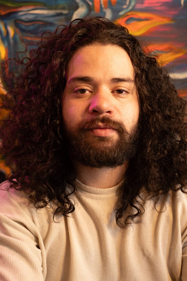 Imagem de Guilherme Marques, fotógrafo profissional, com fundo artístico vibrante.