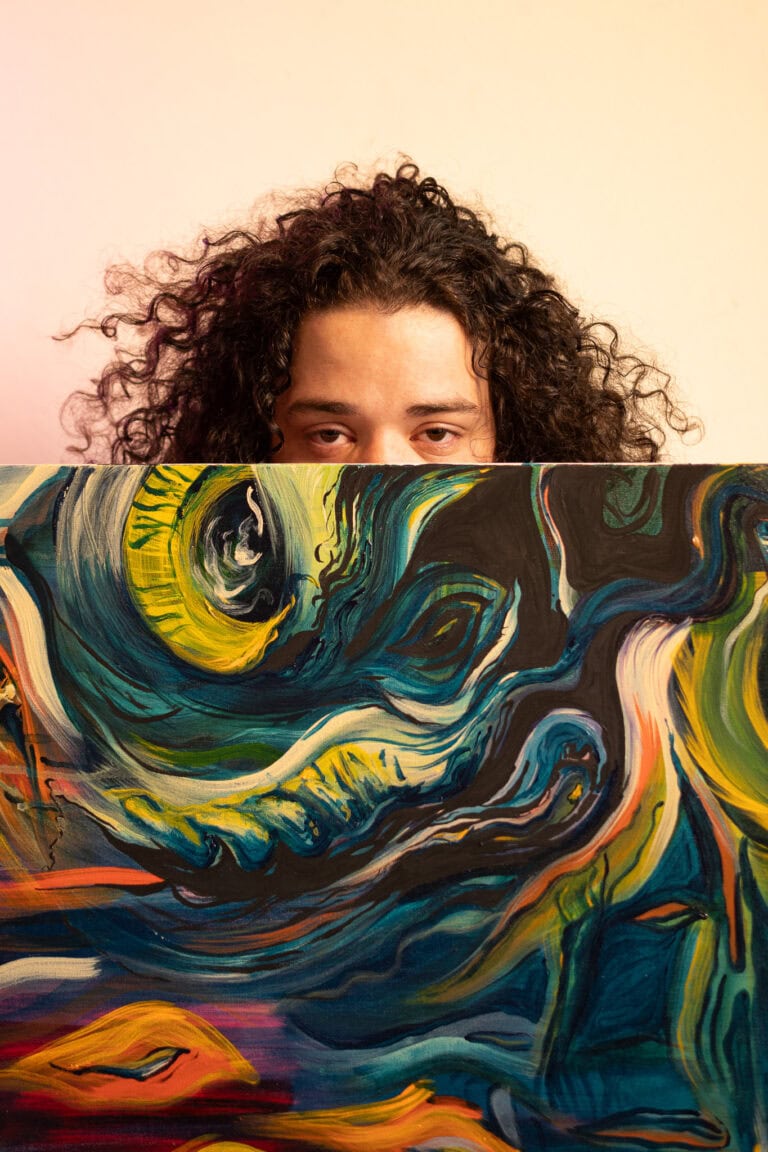 Retrato de mulher com cabelo cacheado segurando quadro de arte abstrata, foco na expressão facial e.