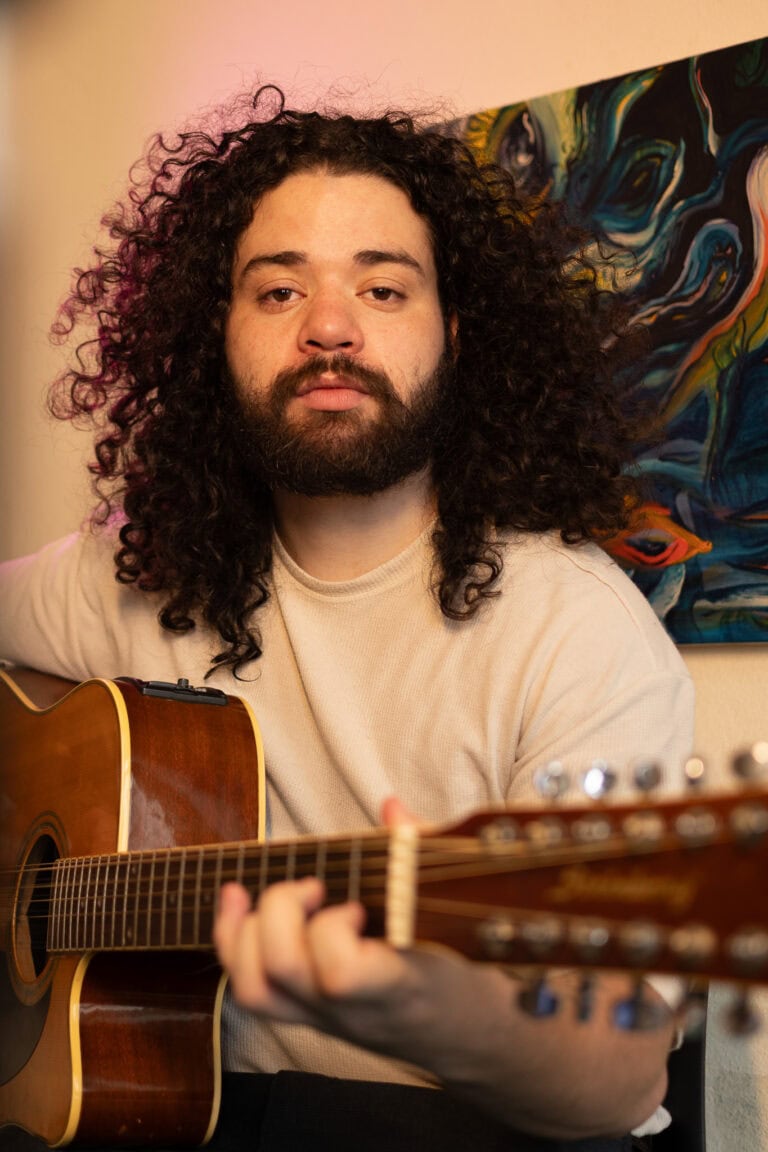 Imagem de Guilherme Marques tocando violão em estúdio.