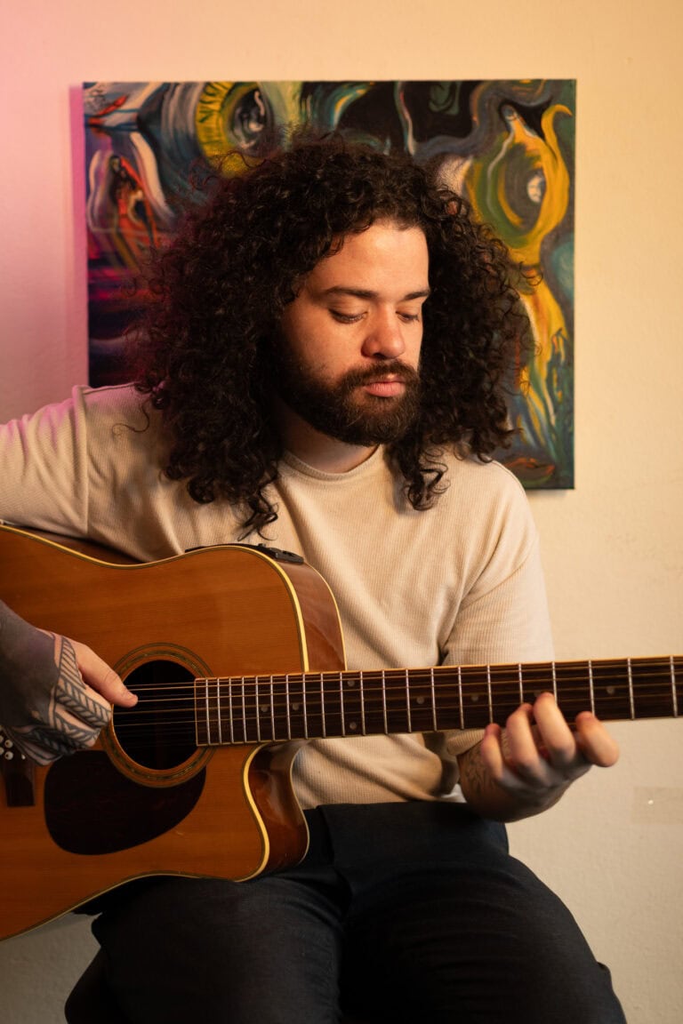 Guilherme Marques tocando violão em ambiente de estúdio.