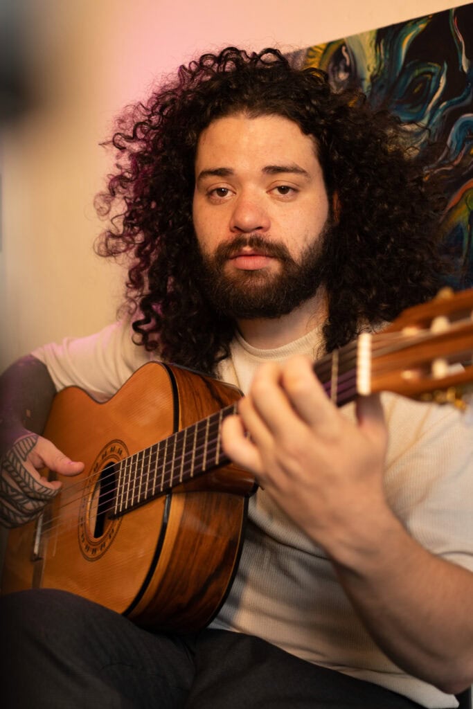 Fotógrafo Guilherme Marques tocando violão em ensaio fotográfico.