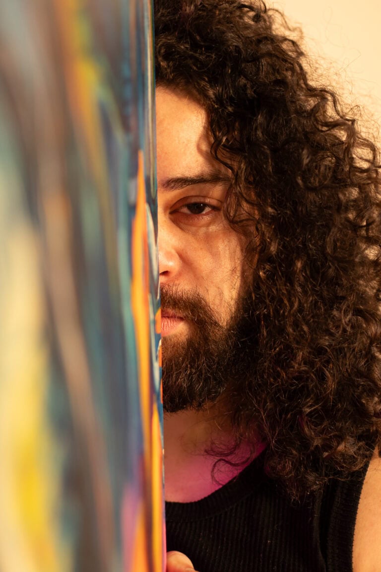 Guilherme Marques, fotógrafo profissional, capturando detalhes de um artista com cabelo cacheado.