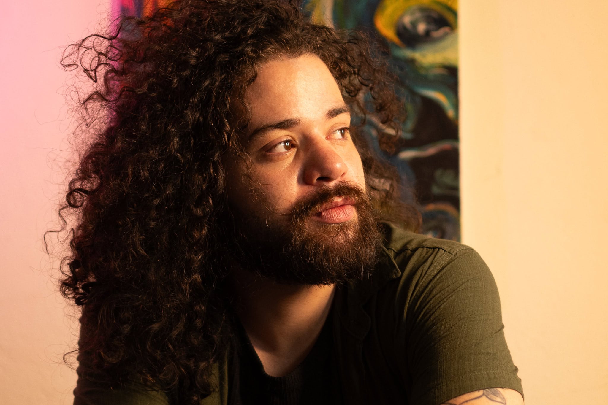 Ensaio para músicos: foto artística de artista com cabelo cacheado e expressão pensativa.