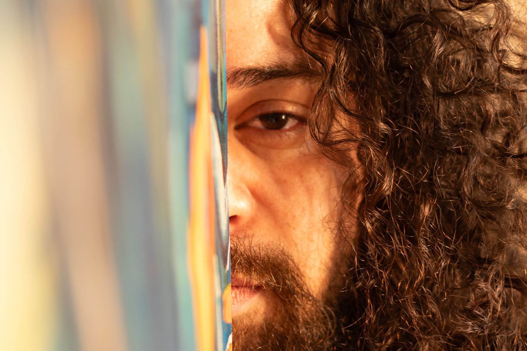 Fotógrafo Guilherme Marques, retrato de um músico com cabelo cacheado, focado na câmera, com fundo a.