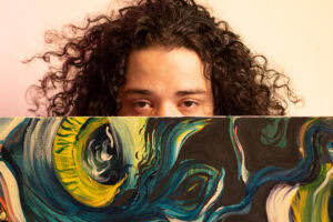 Retrato de pessoa com cabelo cacheado segurando obra de arte abstrata, simbolizando profundidade sim.