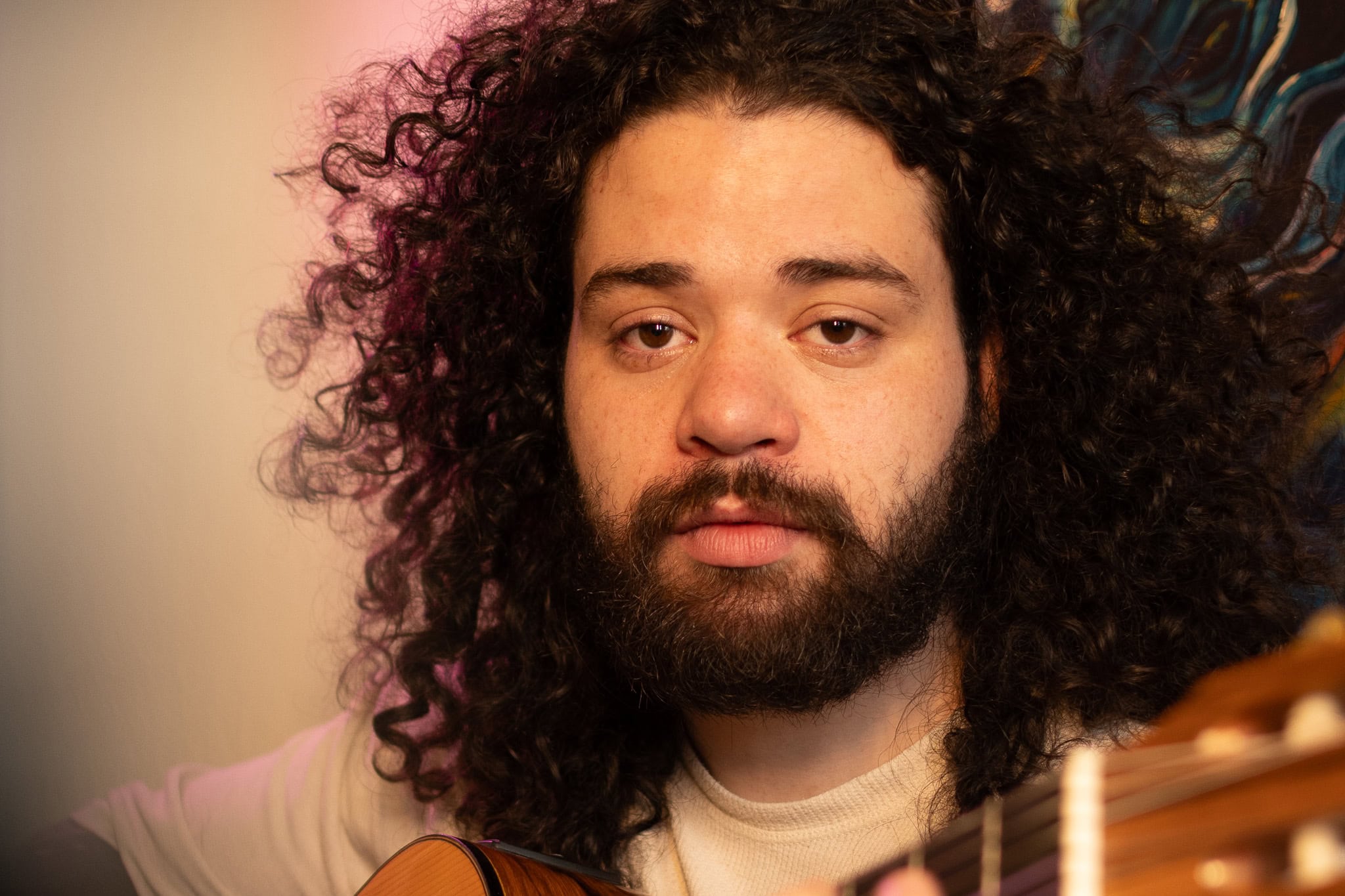 Retrato de músico com cabelo cacheado e violão, focado na produção de ensaio fotográfico para Spotif.