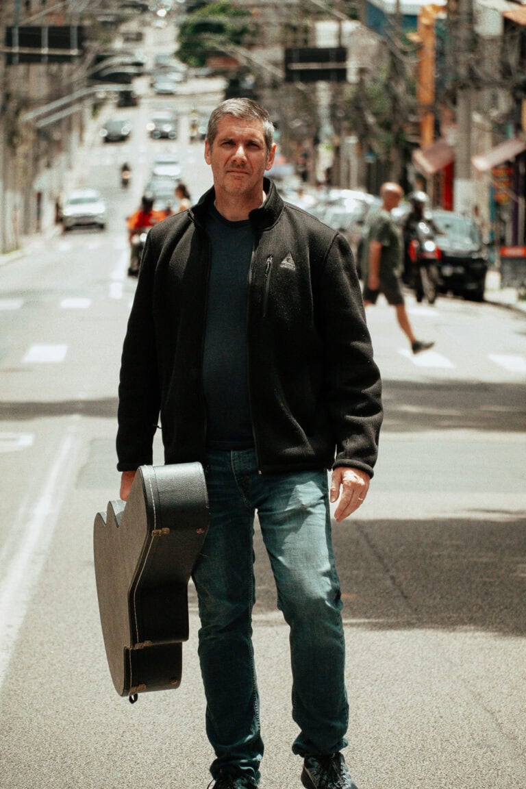 Fotógrafo Guilherme Marques na rua com guitarra.