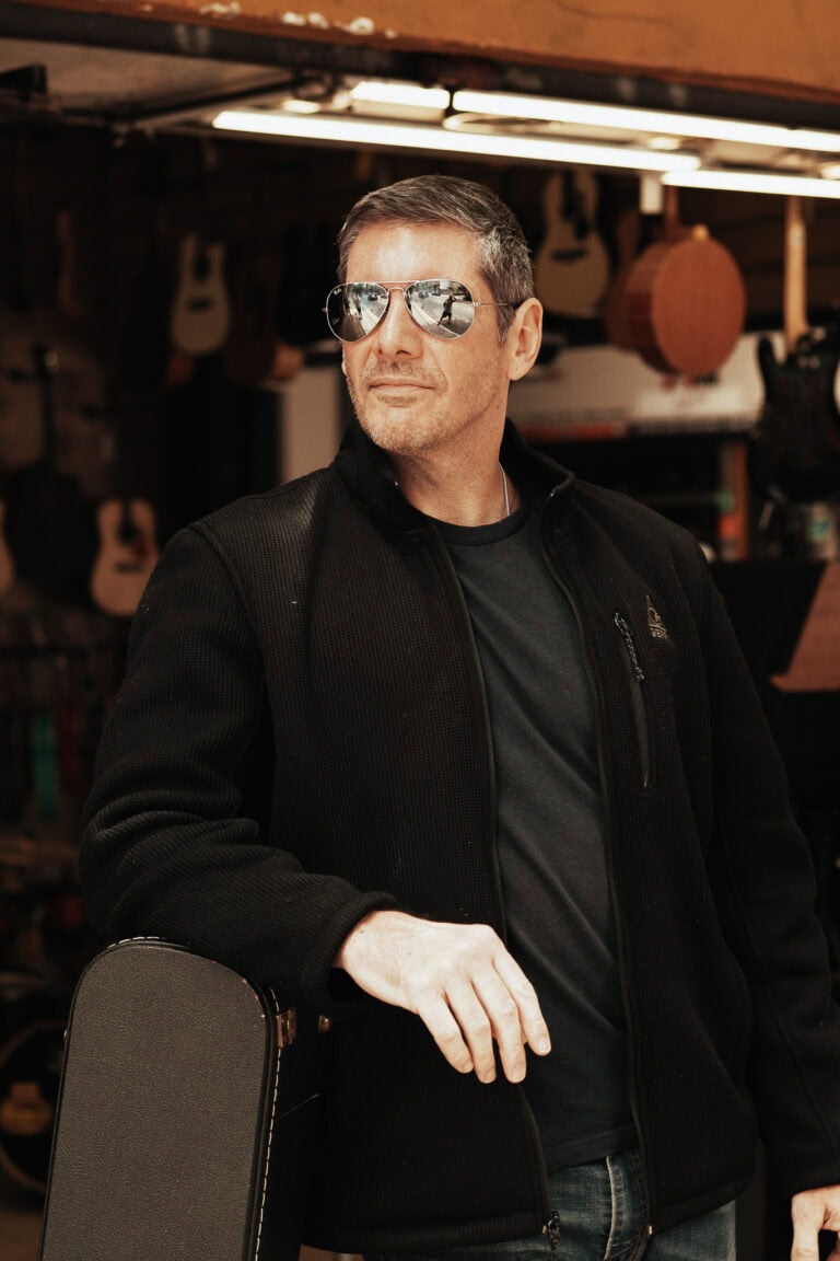 Fotógrafo Guilherme Marques em estúdio de fotografia com guitarra ao fundo.