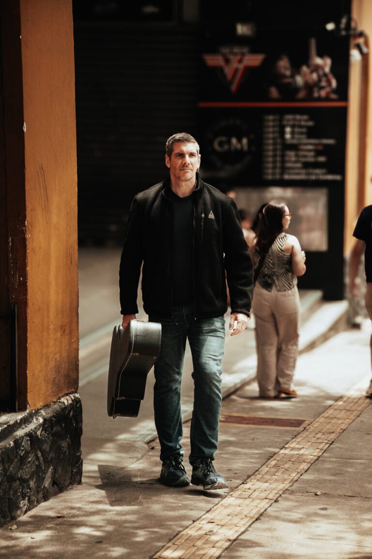 Guilherme Marques, fotógrafo profissional, caminhando na rua com sua câmera e equipamento.