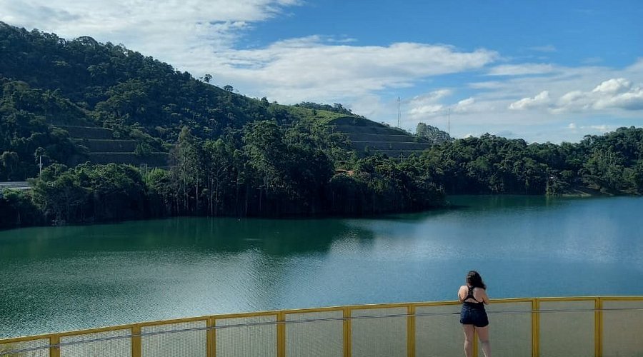 Ensaio de casal em ambiente natural perto de São Paulo, com vista para lago e natureza exuberante.