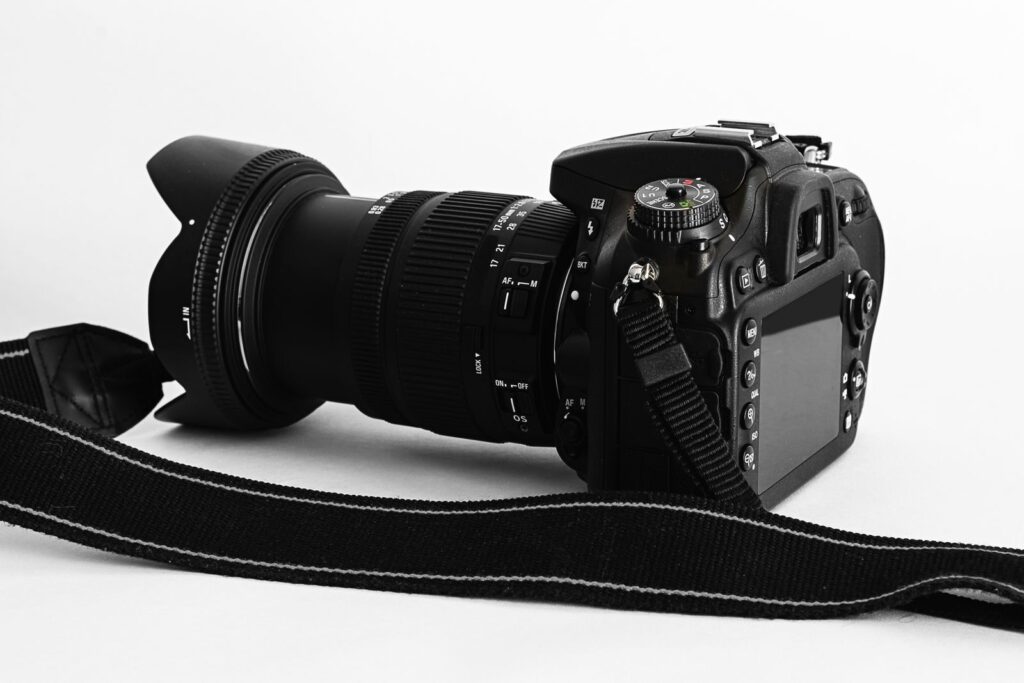 Close-up of a DSLR camera with lens and strap on a white background.