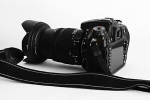 Close-up of a DSLR camera with lens and strap on a white background.