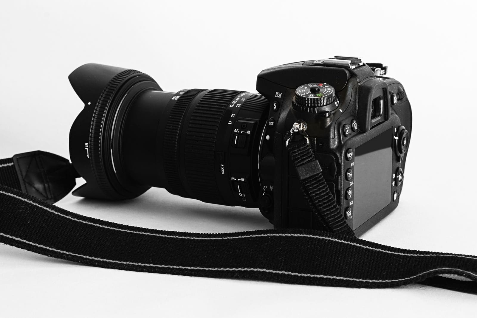 Close-up of a DSLR camera with lens and strap on a white background.