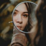 woman holding magnifying glass with brown liquid