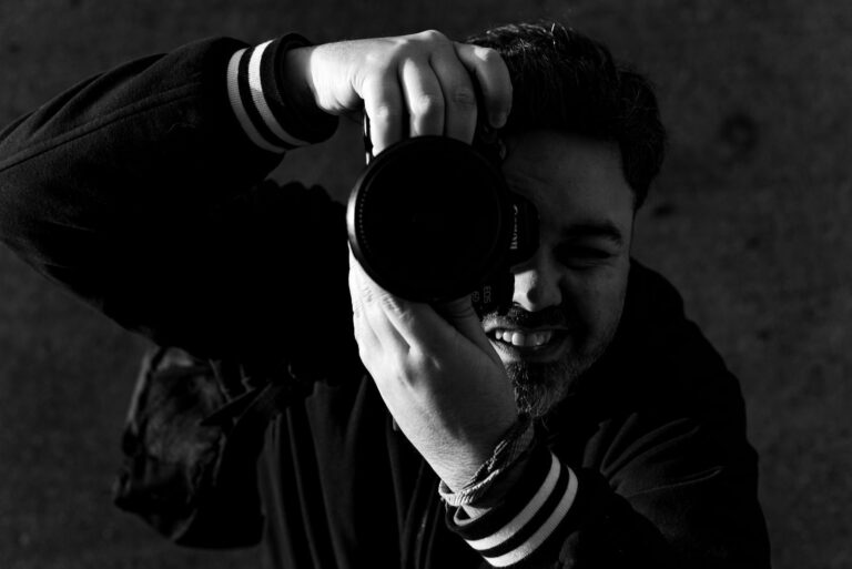 Dynamic black and white portrait capturing a photographer with a camera.