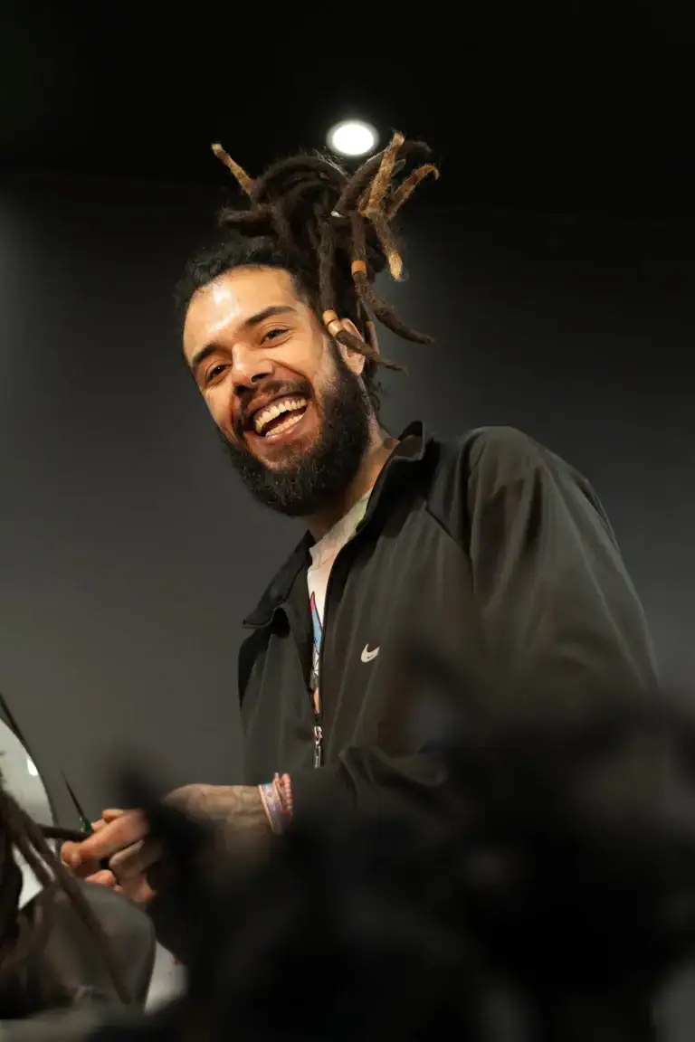 Fotógrafo Guilherme Marques com cabelo dreadlock sorridente em ambiente interno.