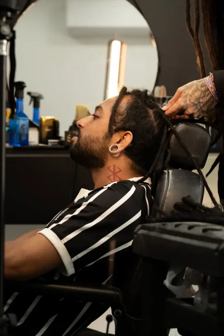 Homem recebendo corte de cabelo em barbearia moderna com espelho redondo.