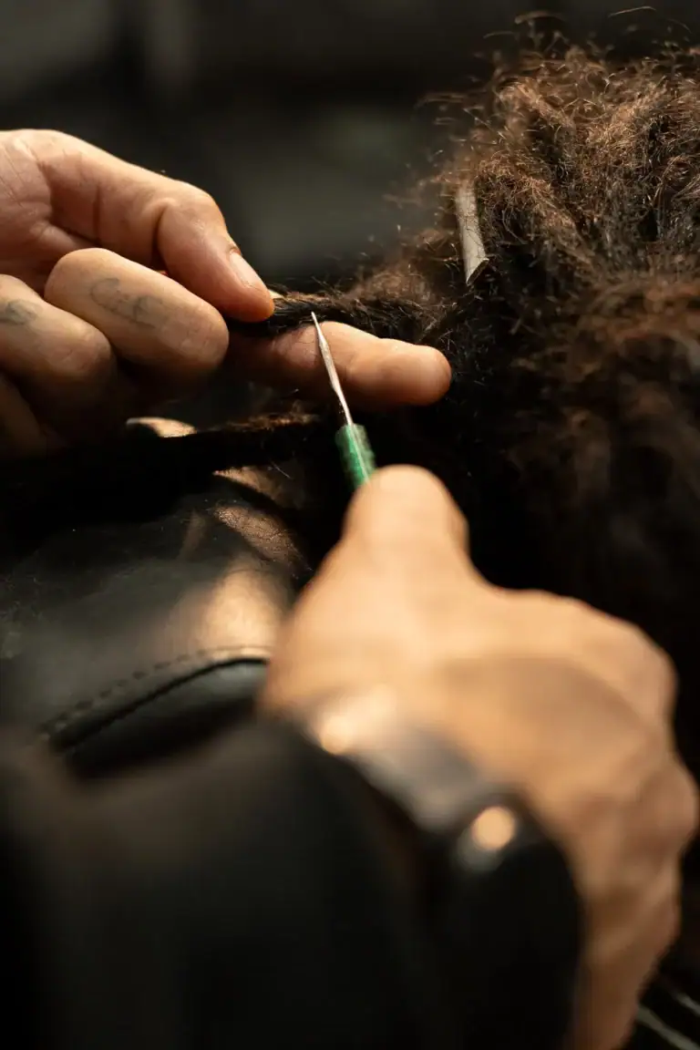 Cabeleireiro aplicando injeção de tinta em cabelo afro.