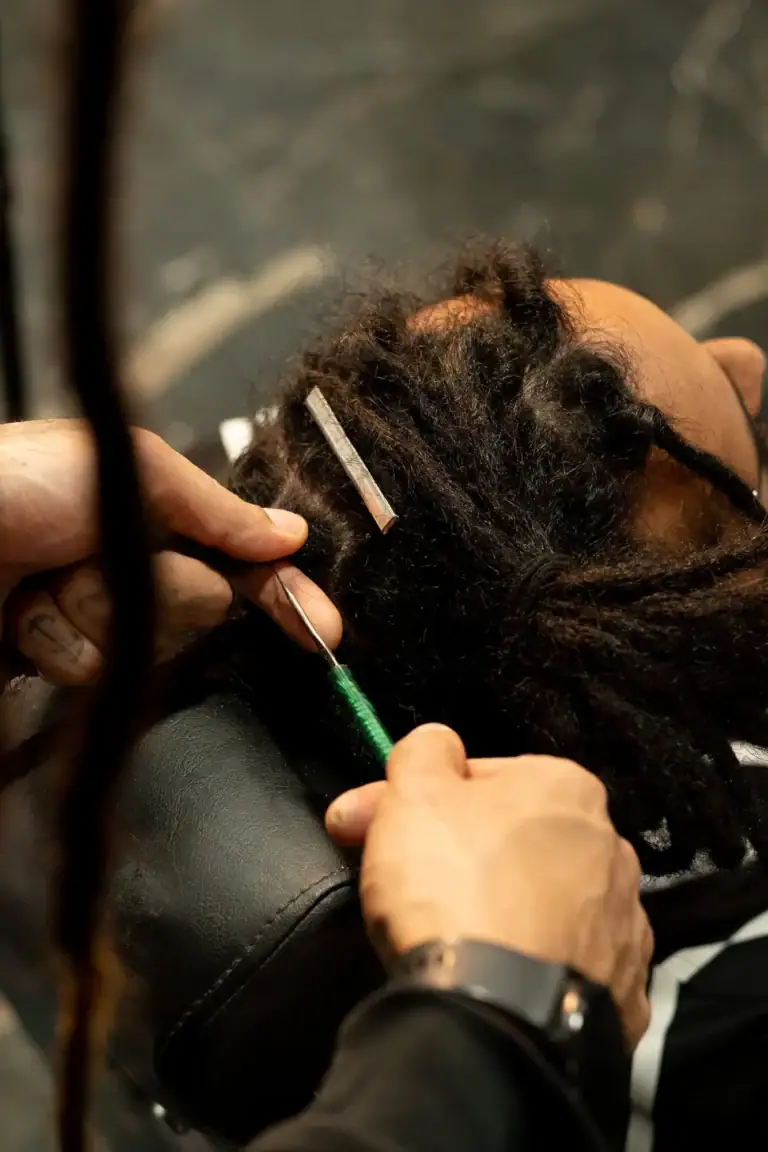 Cabeleireiro aplicando tratamento em dreadlocks de cliente no salão.