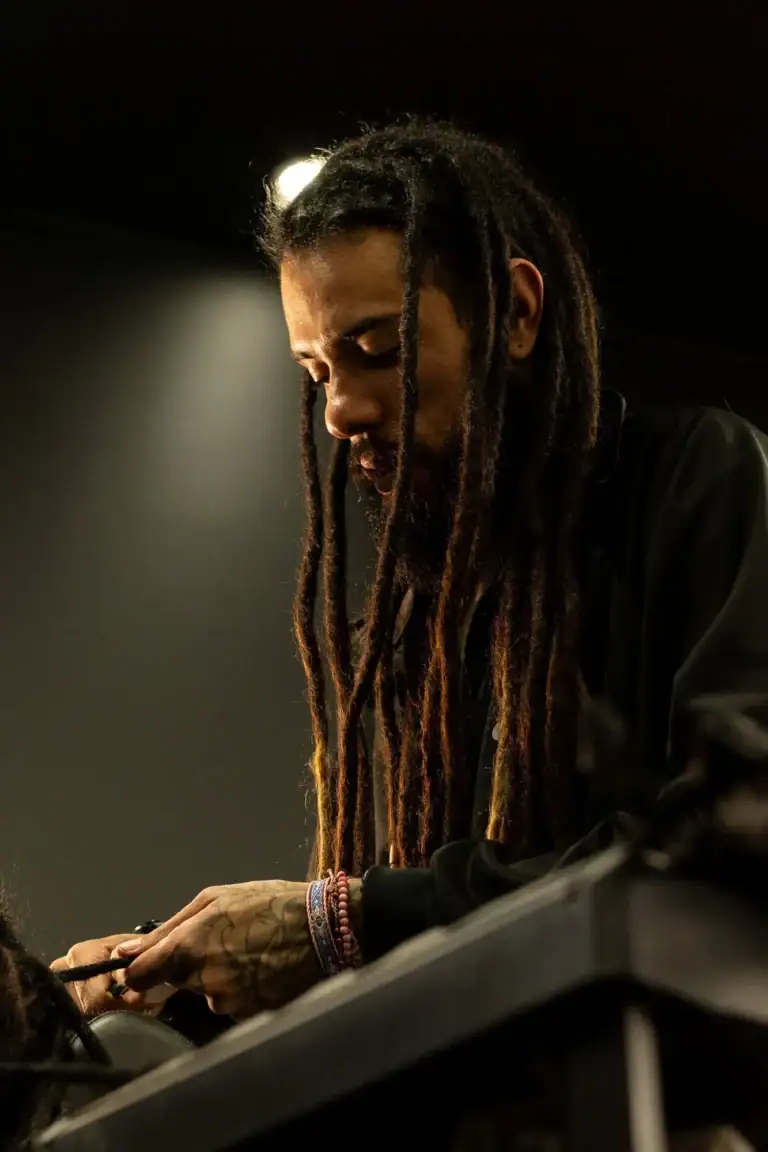 Fotógrafo com dreadlocks concentrado em seu trabalho em estúdio.