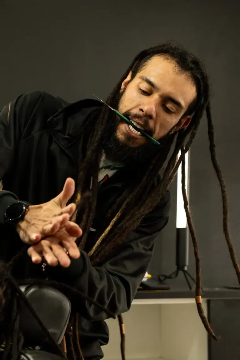 Fotógrafo com dreadlocks ajustando equipamento de fotografia em estúdio.