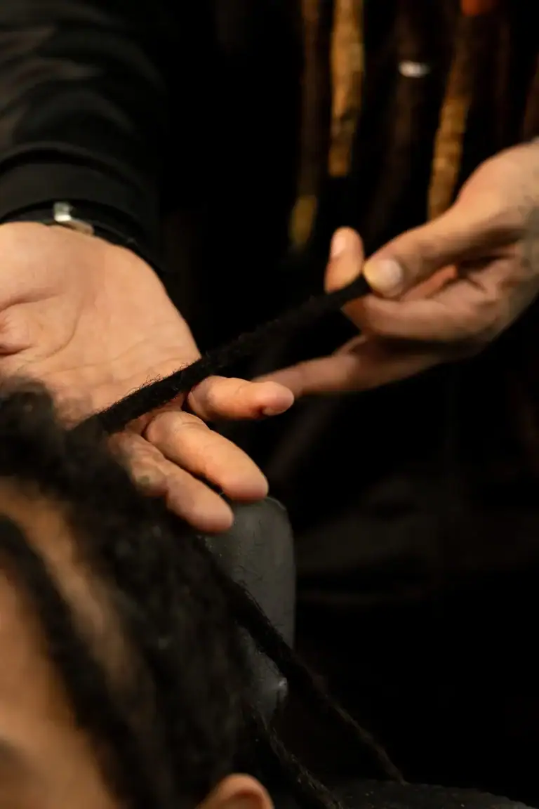 Fotógrafo ajustando dreadlocks em cabelo afro com foco na mão e cabelo.