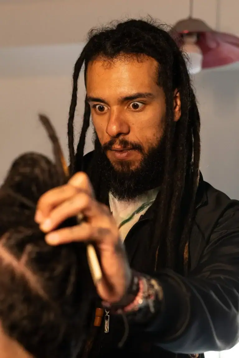 Fotógrafo com dreadlocks ajustando cabelo de modelo em estúdio.