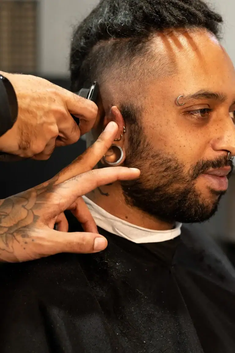 Homem recebendo corte de cabelo em barbearia moderna por fotógrafo Guilherme Marques.