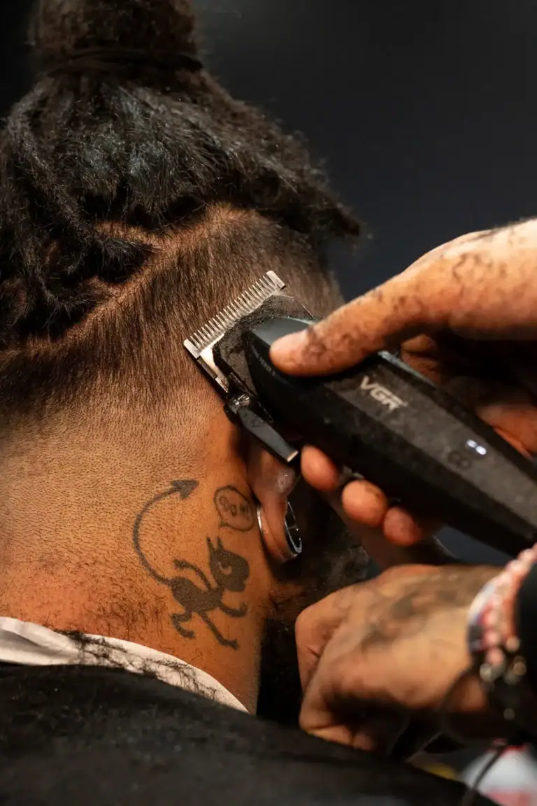 Corte de cabelo com máquina profissional por um barbeiro em ação.