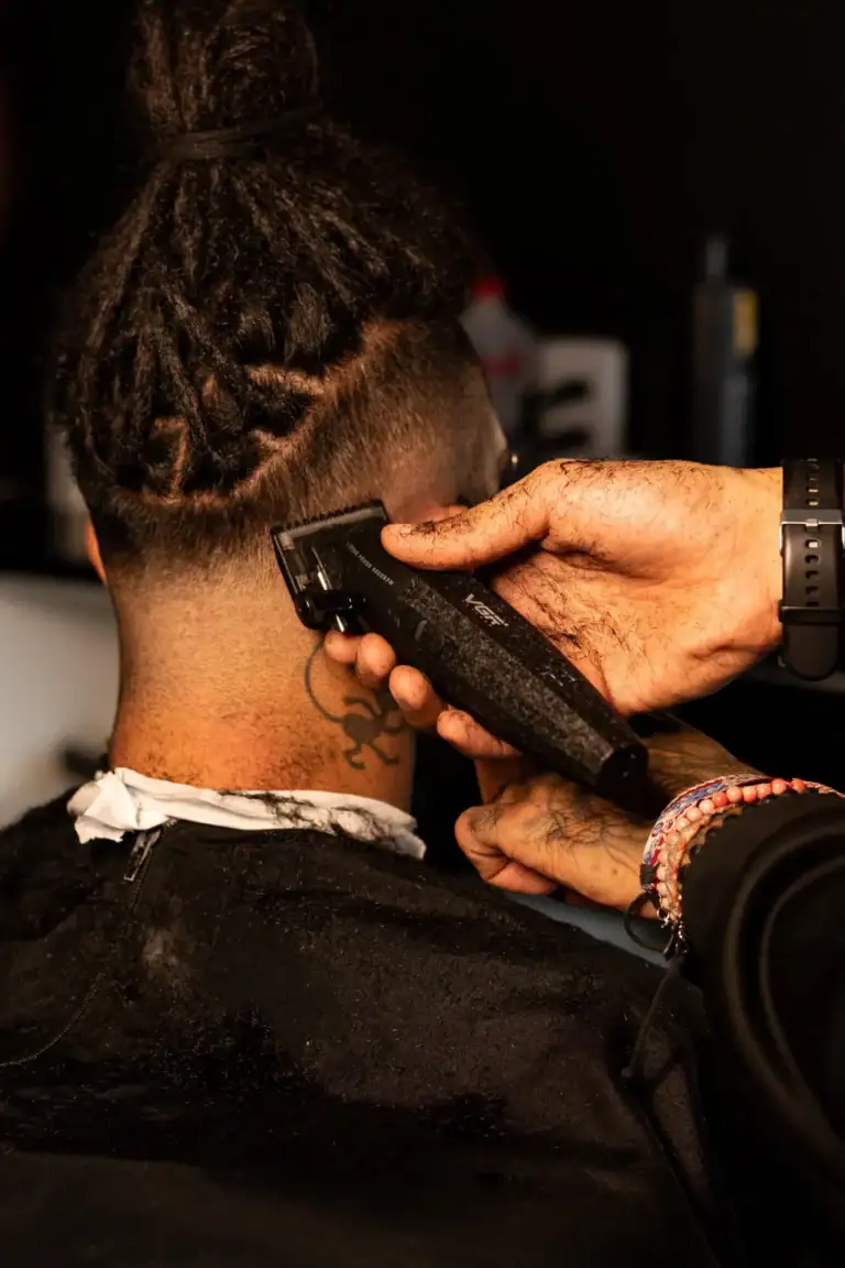 Homem cortando cabelo com máquina de barbear em salão de beleza.
