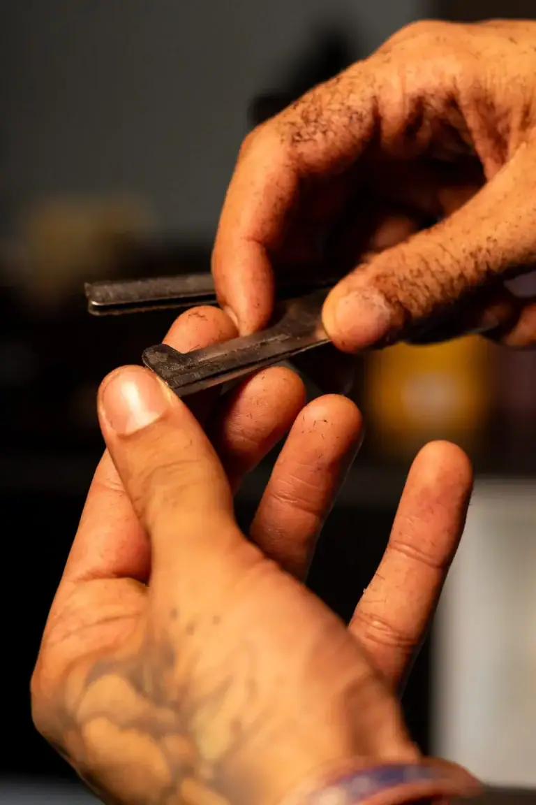 Mãos de tatuador trabalhando com agulha e pele.