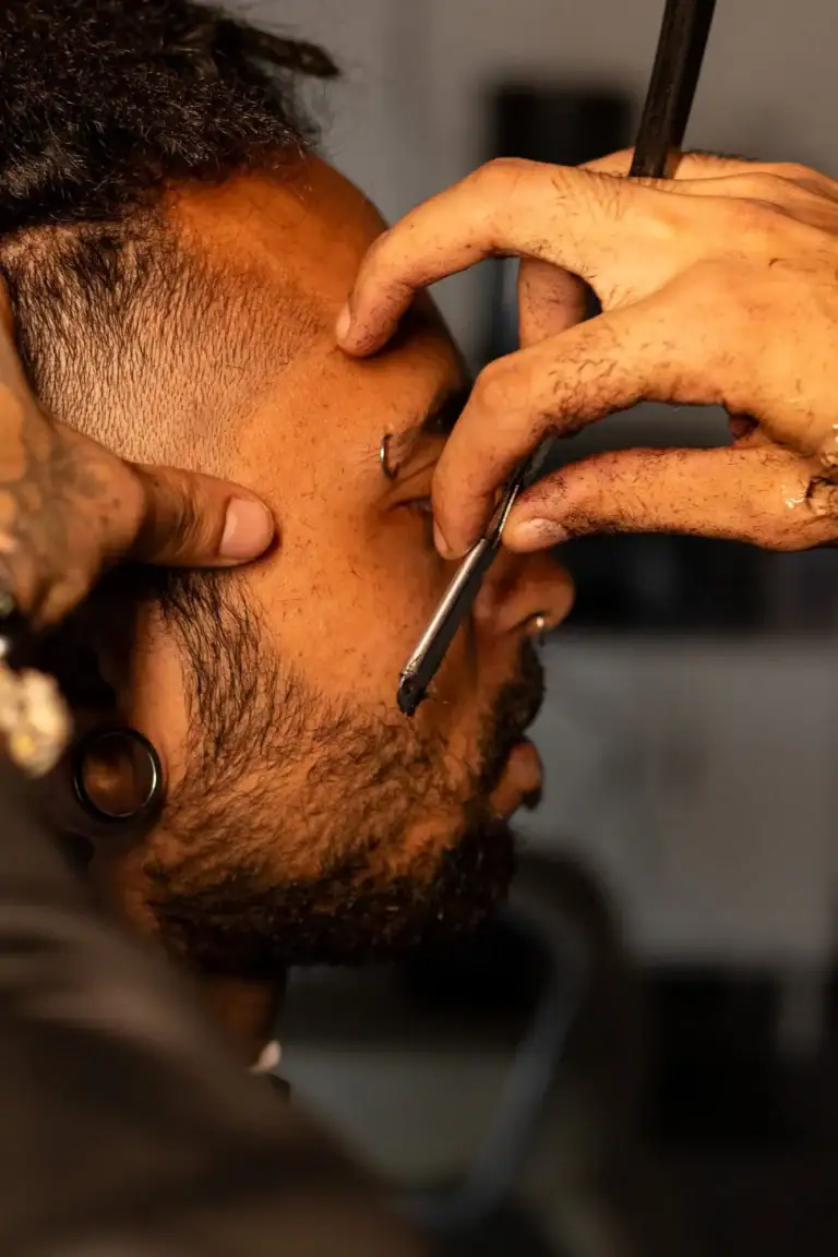 Homem recebendo tatuagem no rosto por tatuador profissional.