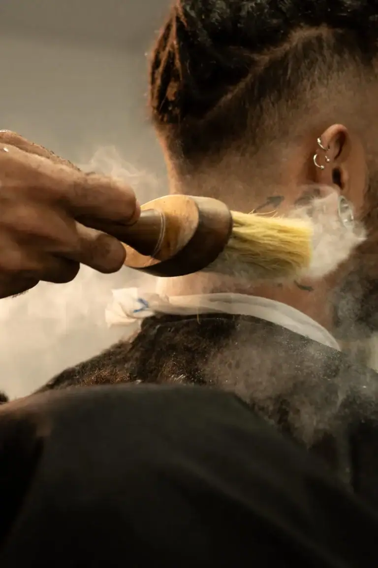 Cabeleireiro aplicando tintura no cabelo de uma cliente com técnica de escovação.