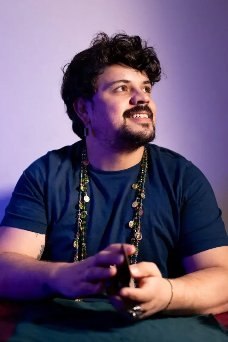 Fotógrafo Guilherme Marques com expressão sorridente e acessórios coloridos.