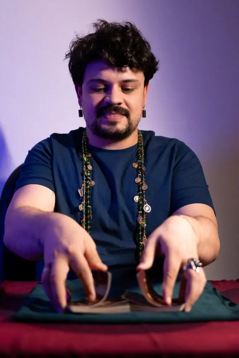 Fotógrafo Guilherme Marques com acessórios, posando com cartas de tarô.